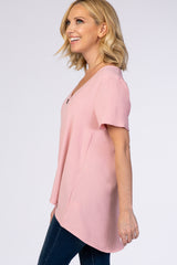 woman wearing a light pink short sleeve top with a v-neck and relaxed fit, paired with dark skinny jeans