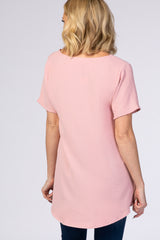 woman wearing a light pink short sleeve top with a longer back hem and a relaxed fit
