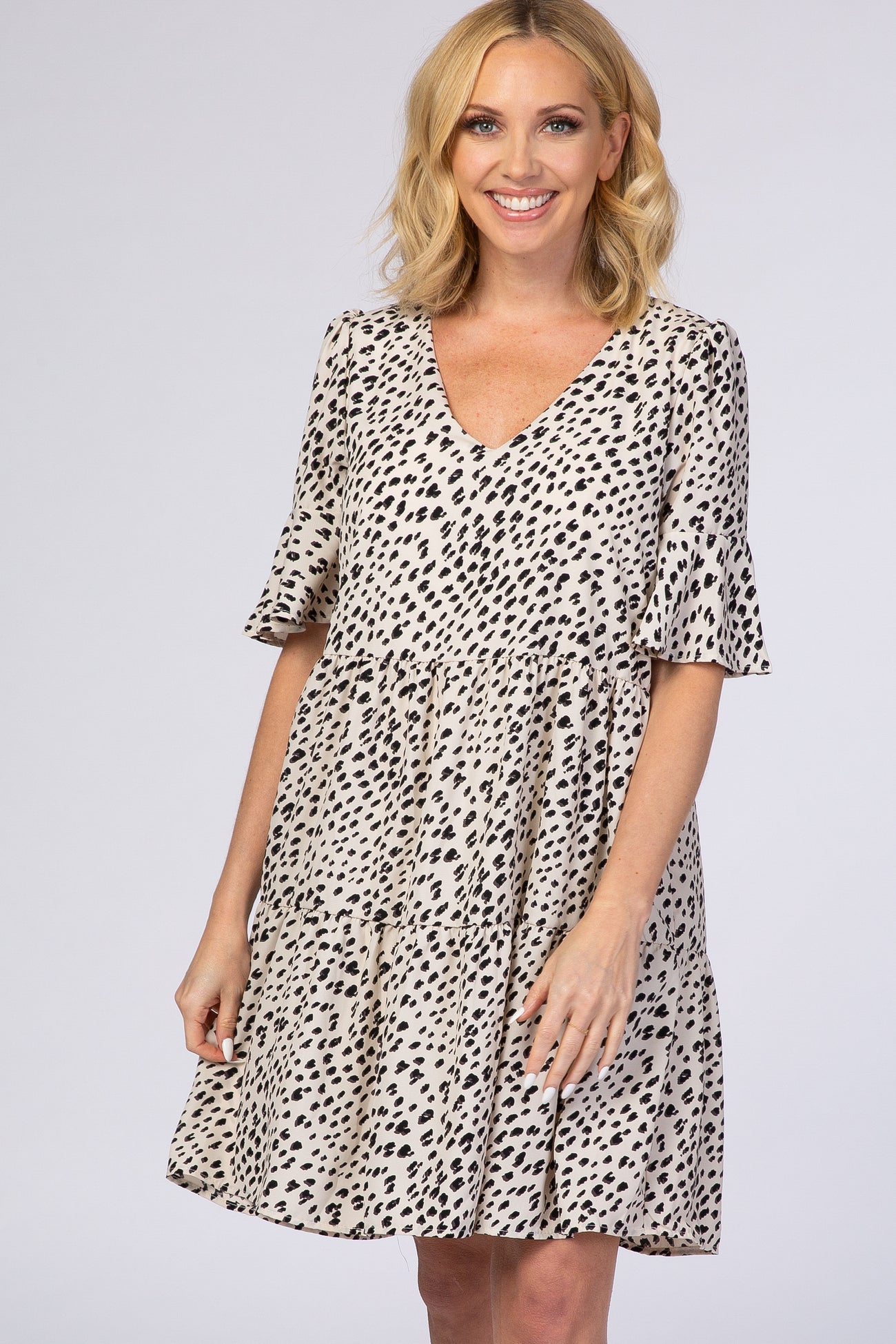 woman wearing a beige spotted short sleeve dress with a v-neckline and a flowing silhouette