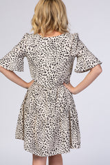 woman wearing a beige and black spotted short sleeve dress with a cinched waist and flared skirt