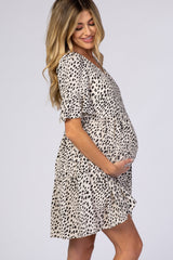 woman wearing a beige short sleeve maternity dress with black spots and showing her baby bump