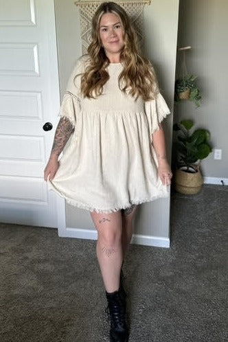 woman wearing a cream babydoll dress with ruffled sleeves and black combat boots