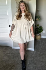 woman wearing a cream babydoll dress with ruffled sleeves and black combat boots