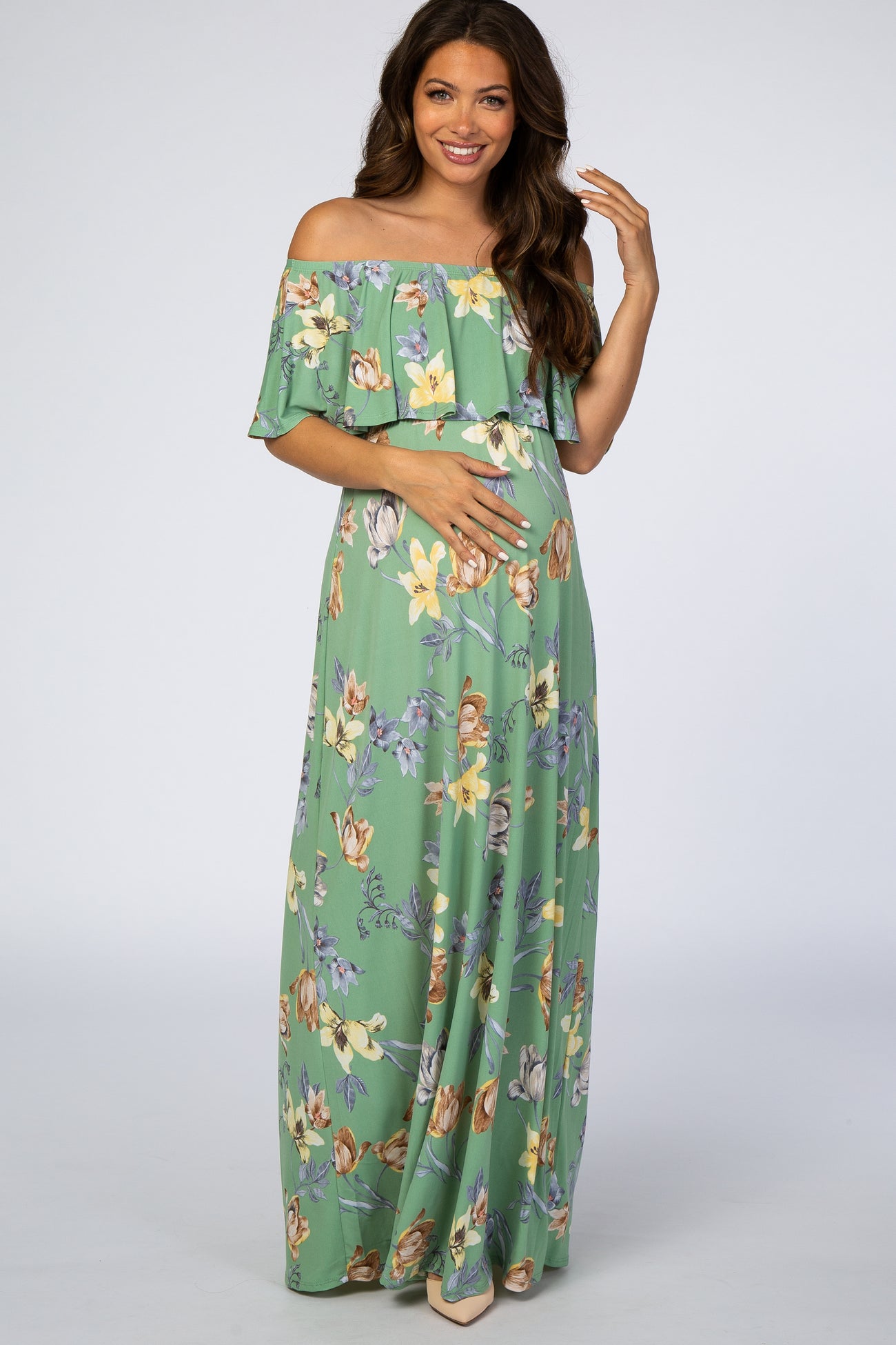 woman wearing a green floral off-the-shoulder maternity maxi dress and holding her baby bump