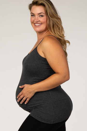 woman wearing a dark gray maternity tank top, gently cradling her baby bump