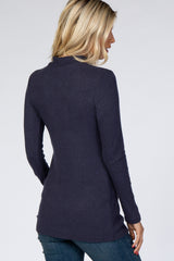 woman wearing a navy long sleeve ribbed tunic sweater, viewed from the back, paired with dark jeans