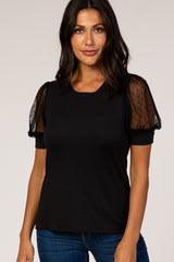 woman wearing a black t-shirt with sheer polka dot puff sleeves and a fitted body style