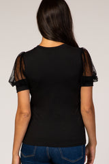black t-shirt with sheer polka dot puff sleeves, worn by a woman facing away, styled with blue jeans