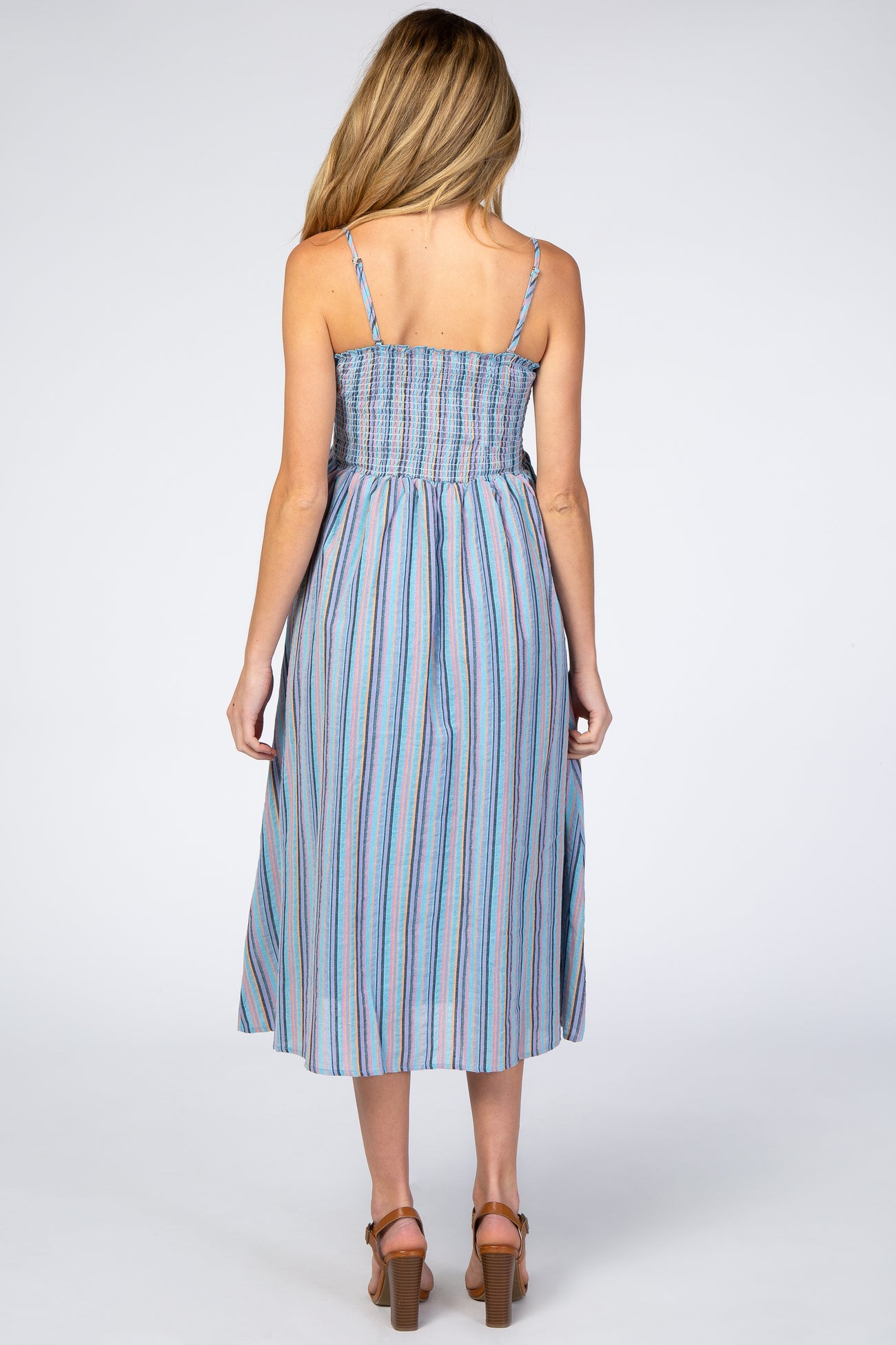 woman wearing a blue striped maternity dress with a smocked bodice and adjustable straps, seen from the back