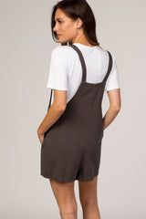 woman wearing a dark gray short overall with a white t-shirt underneath, shown from the back