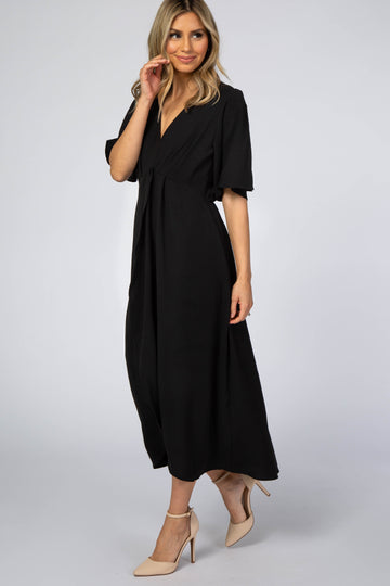 woman wearing a black short sleeve maxi dress with a tie waist and a v-neckline, standing in profile