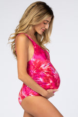 woman wearing a pink tie-dye maternity swimsuit, showcasing her baby bump while smiling