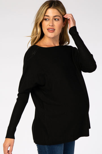 woman wearing a black long sleeve maternity sweater and showing her baby bump