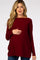 woman wearing a burgundy maternity sweater with a boat neckline and holding her baby bump