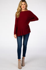 woman wearing a burgundy long sleeve maternity top with blue skinny jeans and tan ankle boots