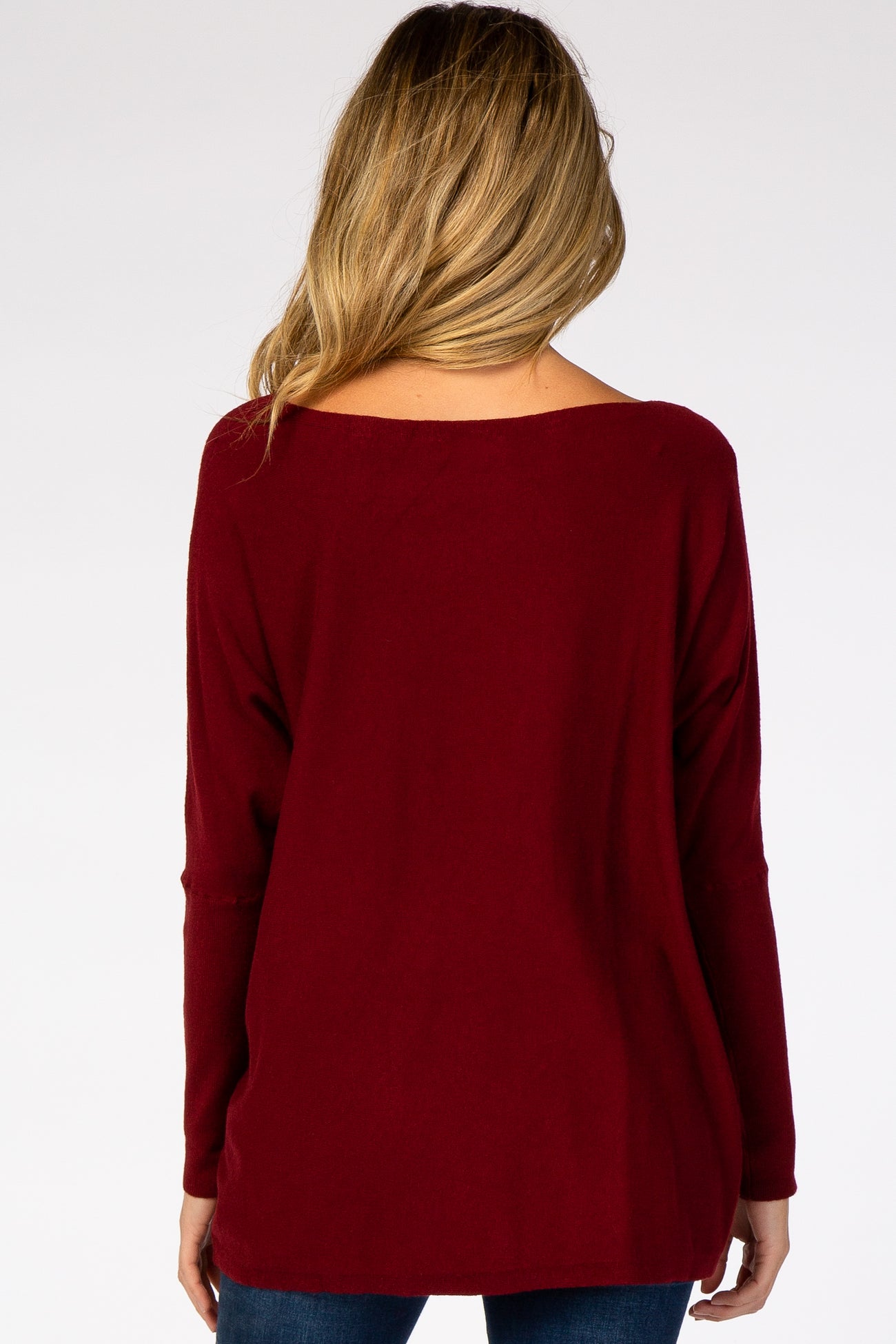 back view of a woman wearing a burgundy long sleeve boat neck sweater
