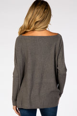 woman wearing a gray maternity sweater with an open back and long sleeves, seen from the back