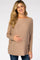 smiling pregnant woman wearing a tan boat neck maternity sweater and blue jeans