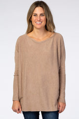 woman wearing a beige oversized sweater with long sleeves and a wide neckline, styled with dark blue jeans