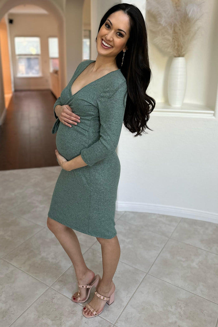 woman wearing a green short sleeve maternity dress and holding her baby bump