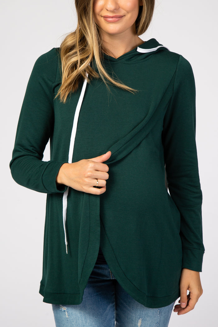 Woman wearing a forest green long sleeve nursing hoodie with white drawstrings and a crossover front design