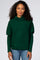 woman wearing a dark green oversized sweater with a cowl neck and long sleeves, paired with blue jeans