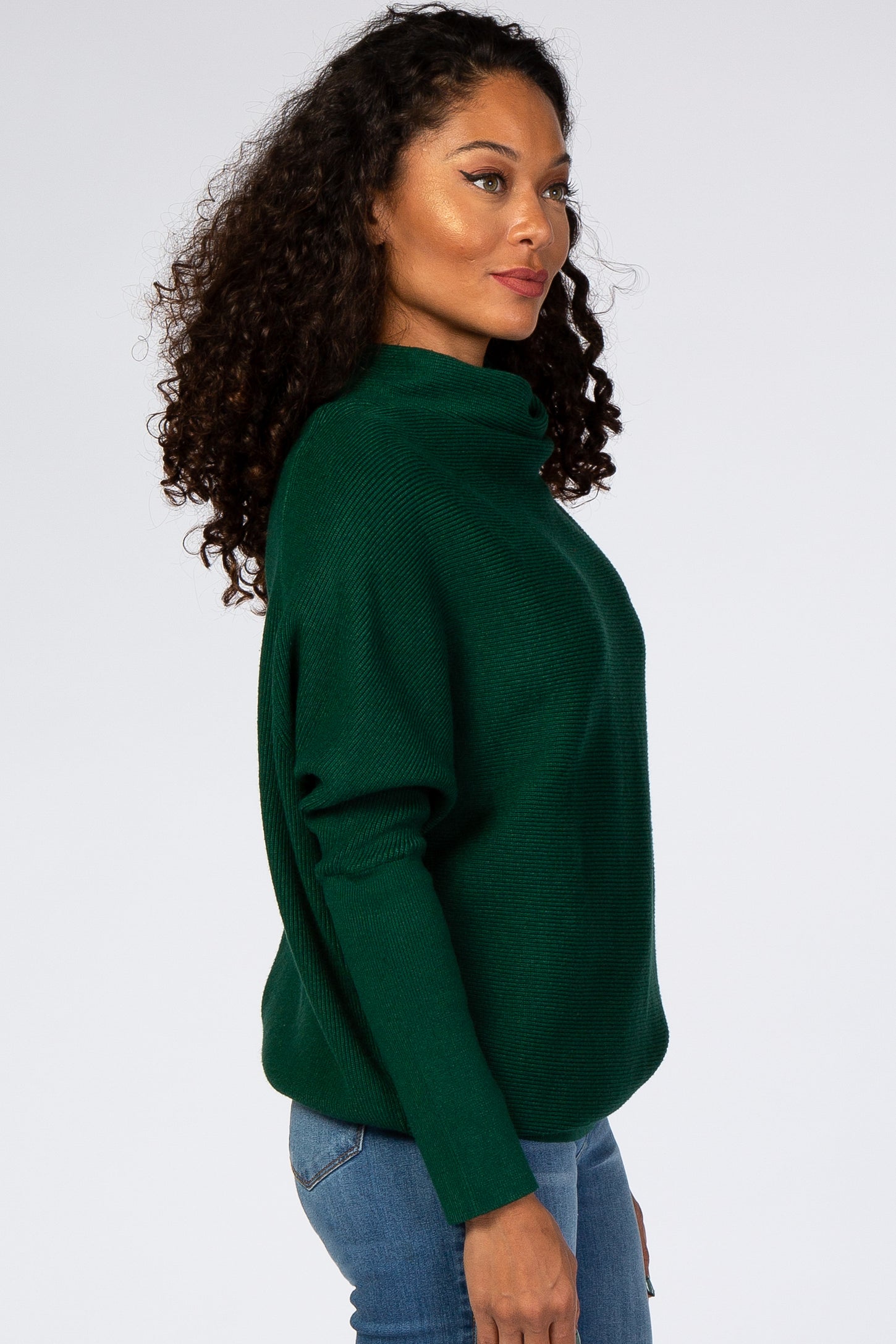 woman wearing a green oversized turtleneck sweater and blue jeans