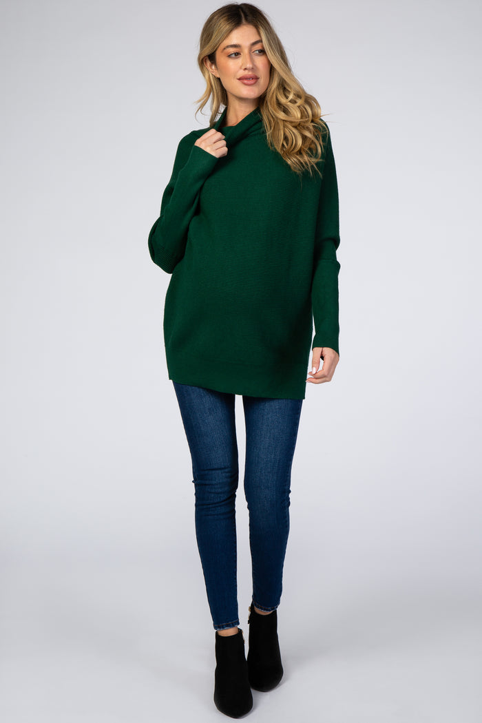 woman wearing a forest green turtleneck sweater with blue skinny jeans and black ankle boots