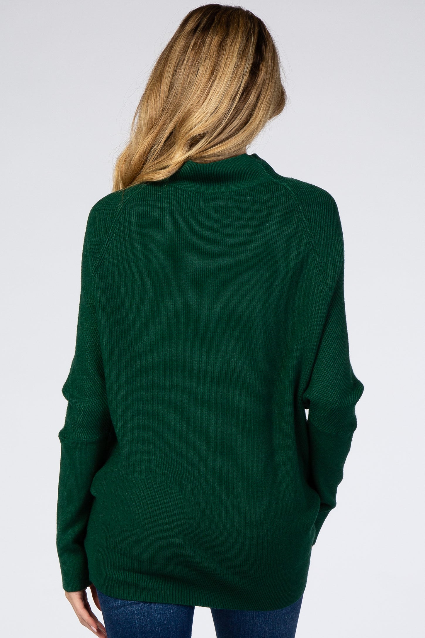woman wearing a dark green oversized maternity sweater, shown from the back