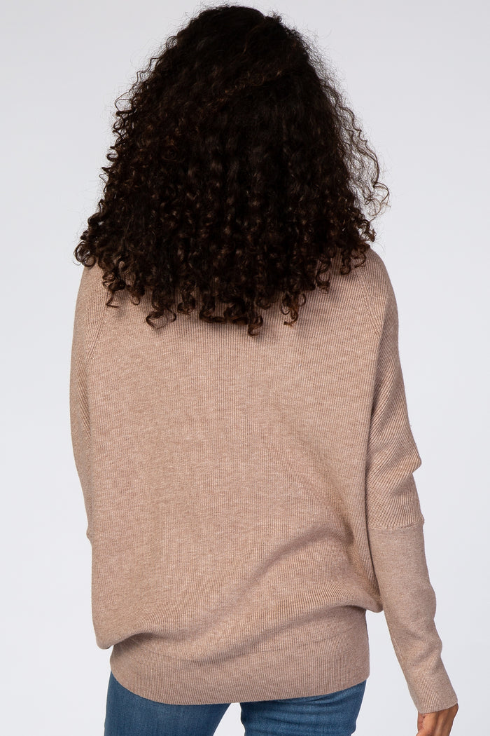 Back view of a woman with curly dark hair wearing a tan ribbed knit sweater and blue jeans