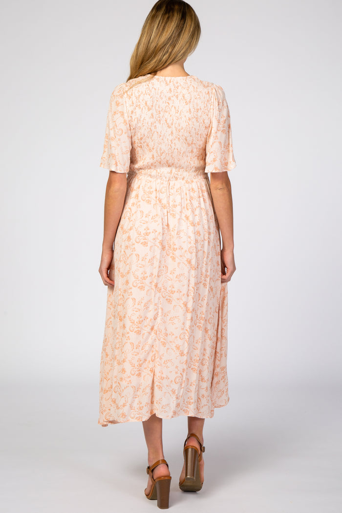 woman wearing a peach floral maternity maxi dress with short sleeves and a smocked bodice, showing the back view