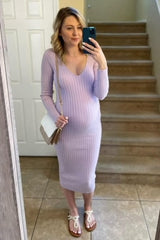 woman wearing a light purple ribbed maternity dress showing her baby bump and holding a purse in front of a mirror