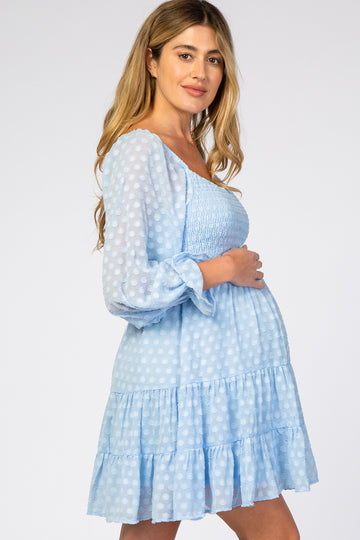 woman wearing a light blue maternity dress with polka dots and a tiered ruffle skirt, showcasing her baby bump