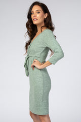 woman wearing a green three-quarter sleeve wrap dress with a tie at the waist