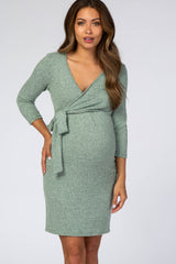 woman wearing a green wrap maternity dress with three-quarter sleeves and a baby bump visible