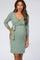 woman wearing a green wrap maternity dress with three-quarter sleeves and a baby bump visible