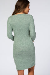 woman wearing a long sleeve green maternity dress, viewed from the back