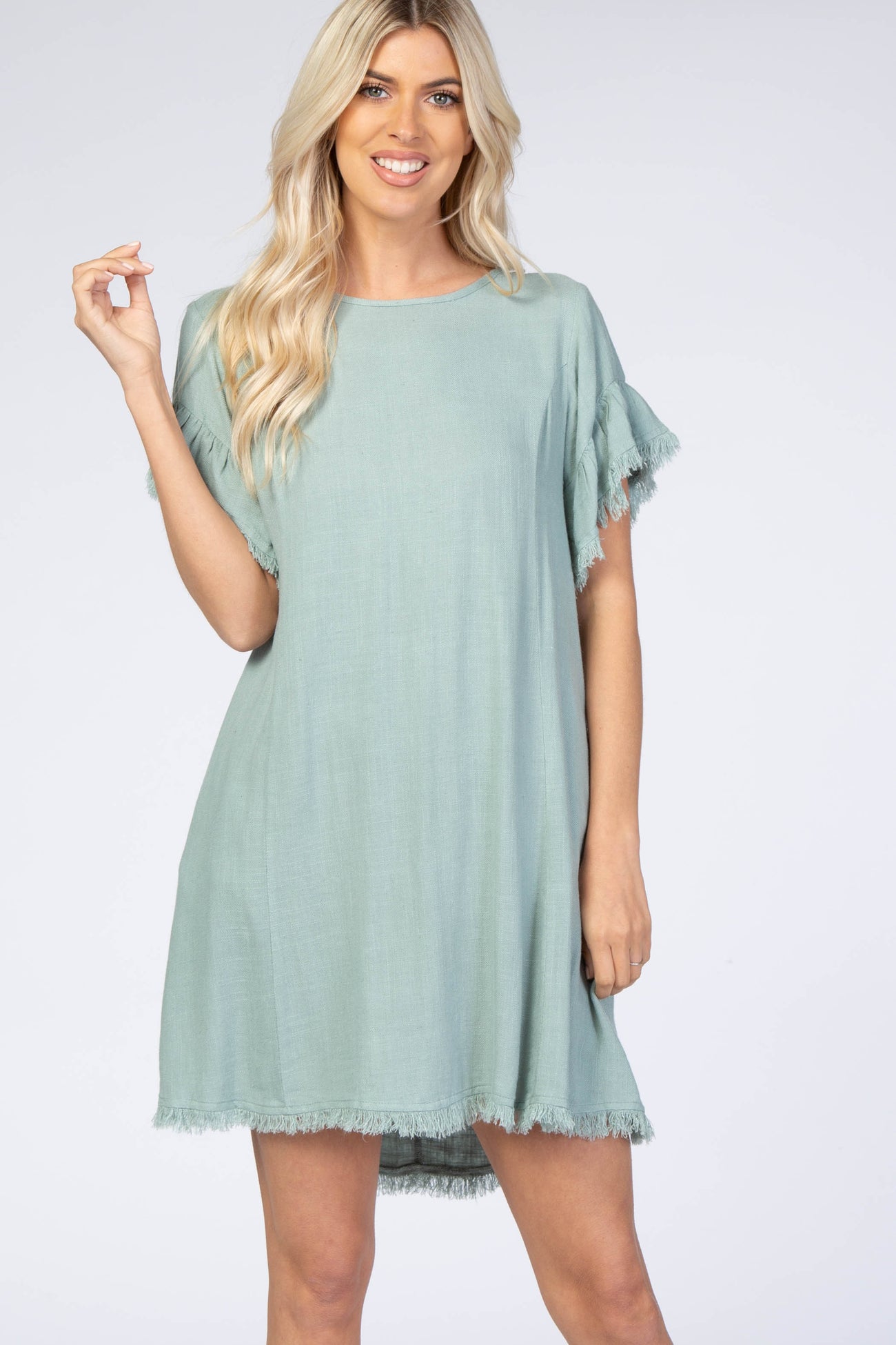 woman wearing a light green short sleeve dress with fringe hem details and relaxed fit