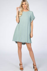 woman wearing a light green short sleeve dress with frayed hem details and standing in a relaxed pose