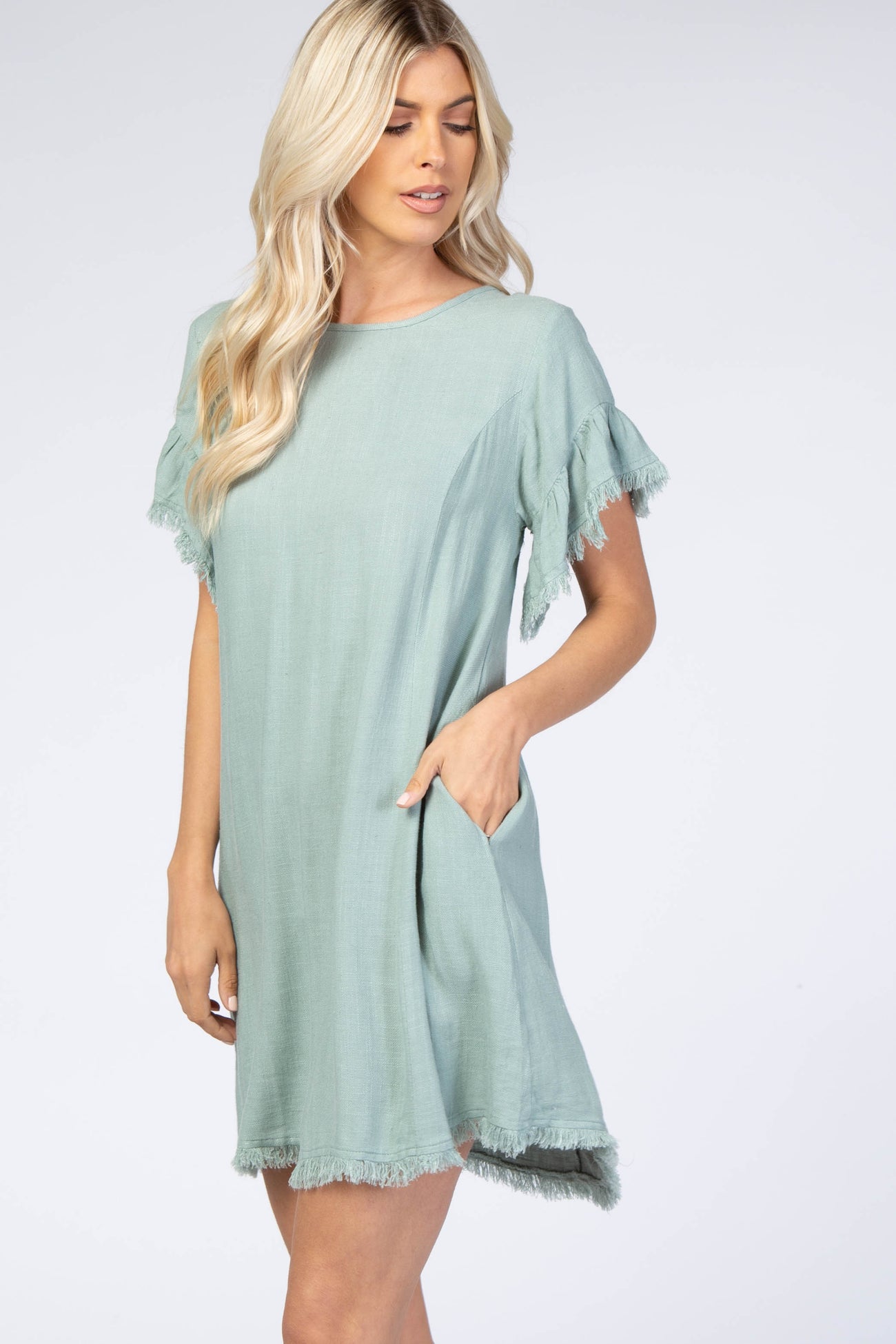 woman wearing a light green short sleeve dress with fringe details and pockets