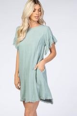 woman wearing a light green short sleeve dress with fringe details and pockets