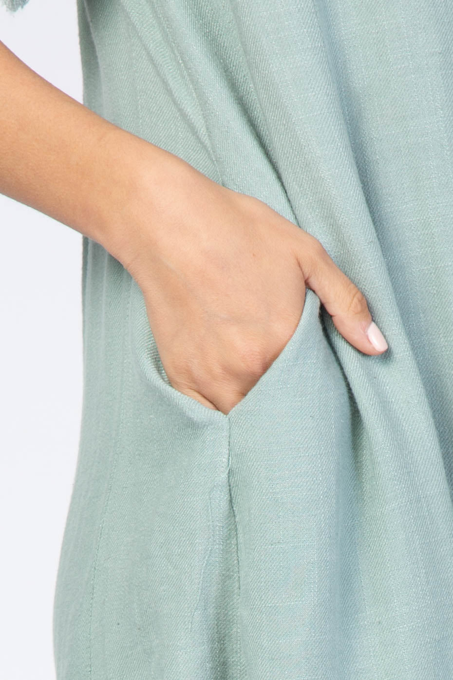 close-up of a woman's hand in the pocket of a light green dress with a relaxed fit