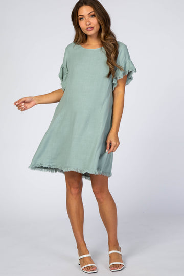 woman wearing a light green maternity dress with fringe detailing at the sleeves and hem
