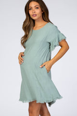 woman wearing a light green maternity dress with ruffled sleeves and pockets, showcasing her baby bump
