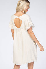 woman wearing a light beige short sleeve dress with a back cutout and fringed sleeves
