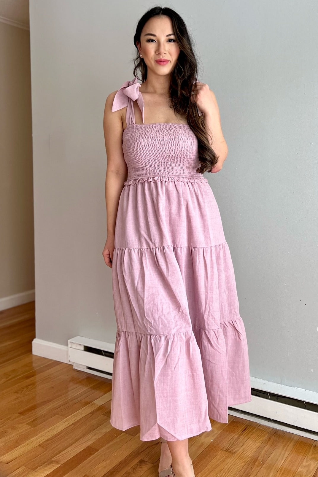 woman wearing a pink smocked maxi dress with shoulder tie details and tiered skirt