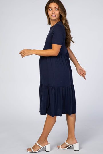 woman wearing a navy blue short sleeve maternity dress with a tiered hem and a visible baby bump