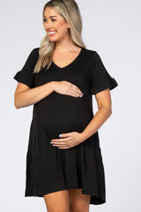 woman wearing a black short sleeve maternity dress with ruffled sleeves and holding her baby bump