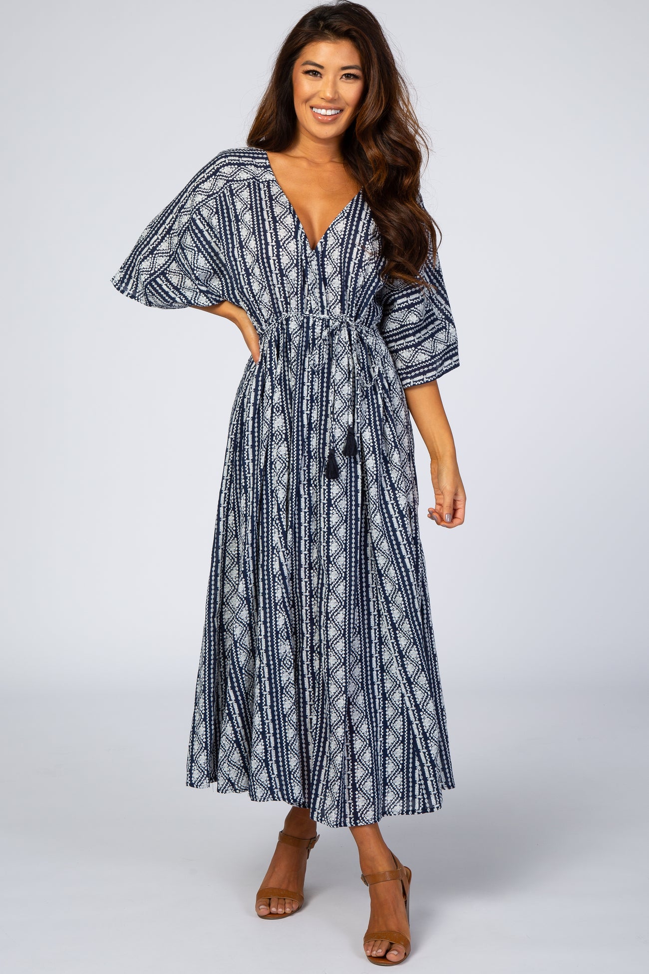 woman wearing a navy blue and white patterned maxi dress with a cinched waist and wide sleeves