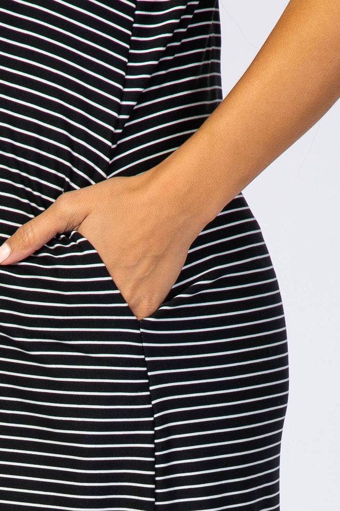 close up of a person's hand in the side pocket of a black and white striped dress